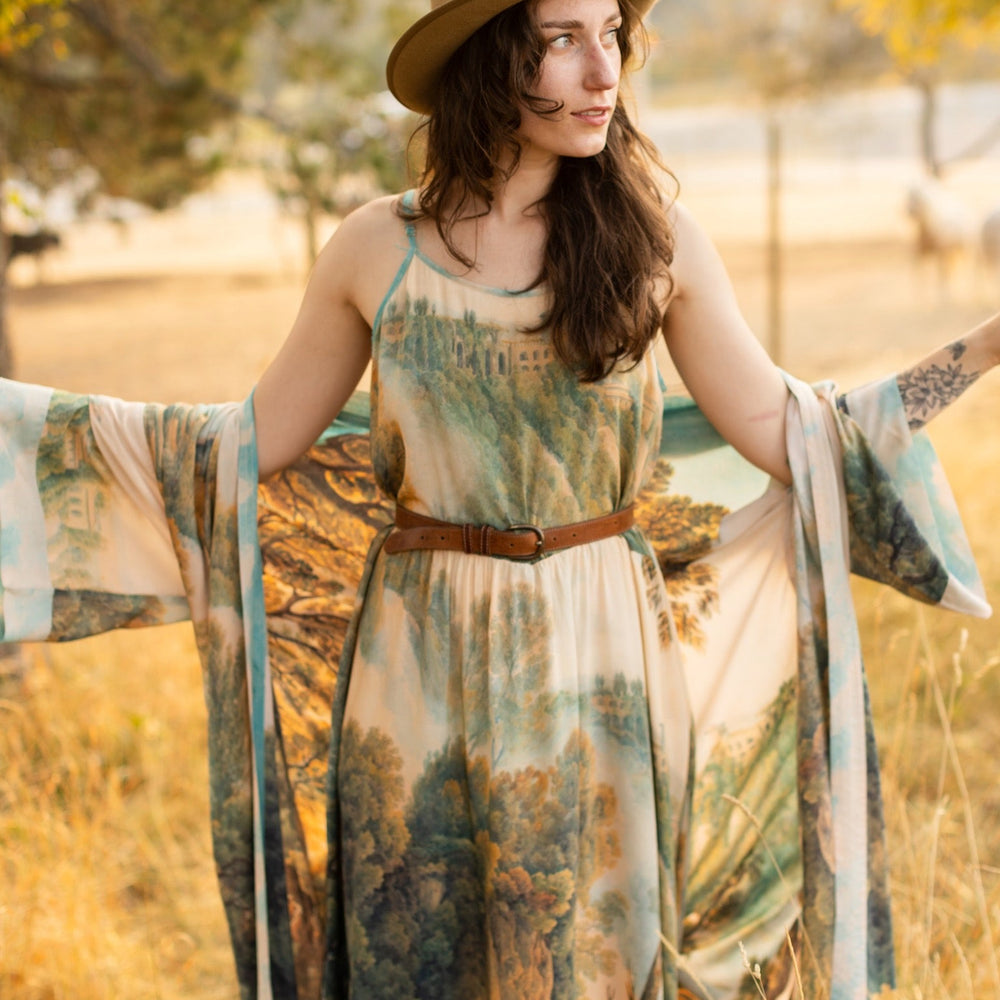 
                  
                    Soft bamboo viscose Bohéme slip dress featuring 18th-century Tivoli waterfalls and Lady Liberty artwork, designed to celebrate self-love and personal power – Market of Stars.
                  
                