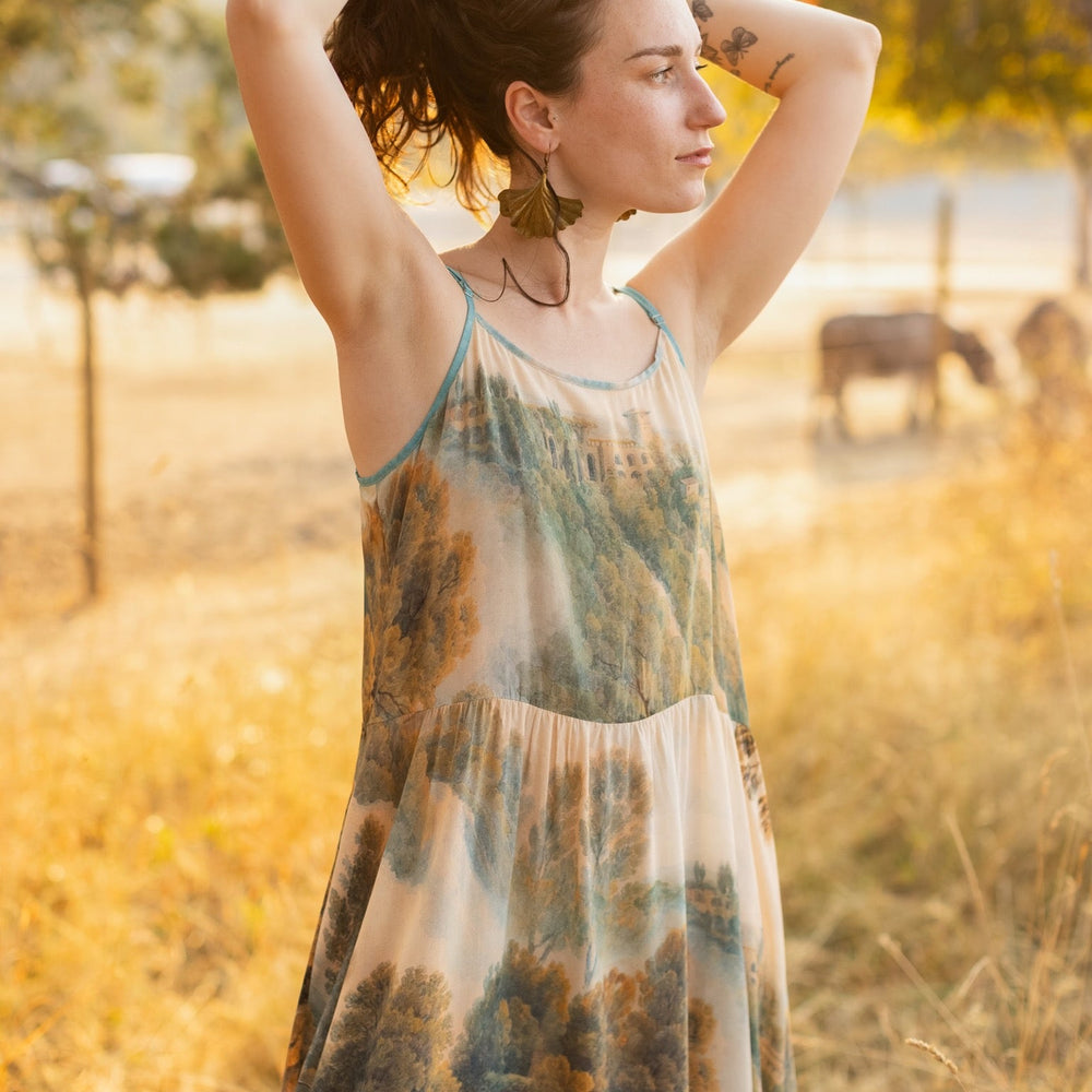 
                  
                    Soft bamboo viscose Bohéme slip dress featuring 18th-century Tivoli waterfalls and Lady Liberty artwork, designed to celebrate self-love and personal power – Market of Stars.
                  
                