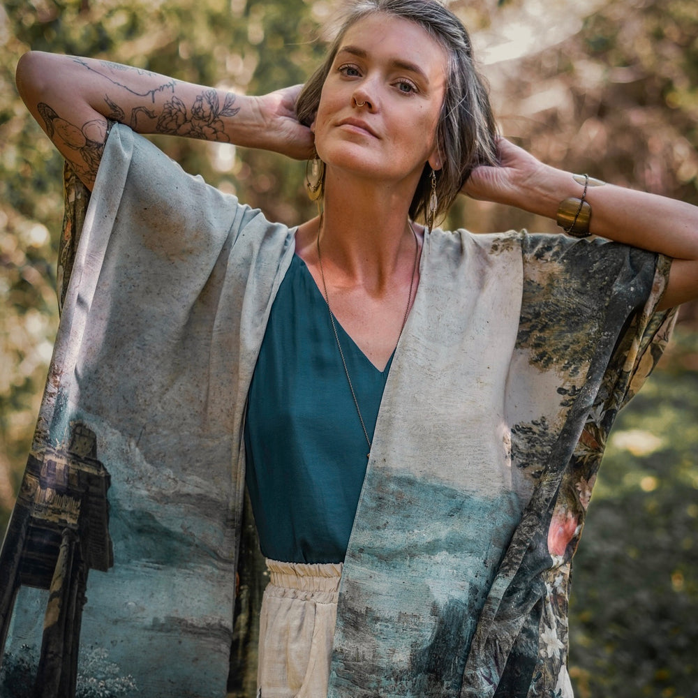 
                  
                    Castles in the Air Starduster kimono featuring Brueghel’s 1600s landscape, classical ruins, and joyful swing scene on bamboo-based viscose – Market of Stars.
                  
                