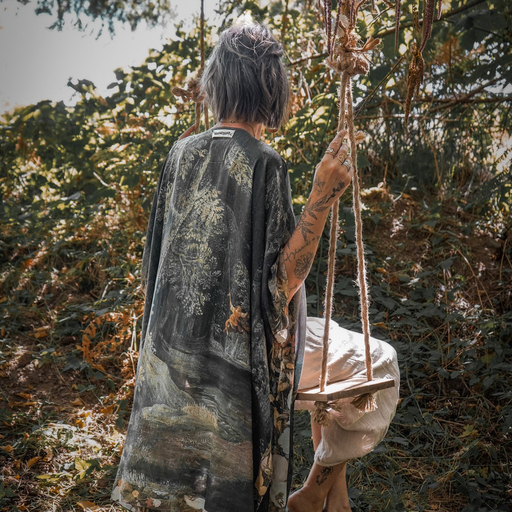 
                  
                    Castles in the Air Starduster kimono featuring Brueghel’s 1600s landscape, classical ruins, and joyful swing scene on bamboo-based viscose – Market of Stars.
                  
                