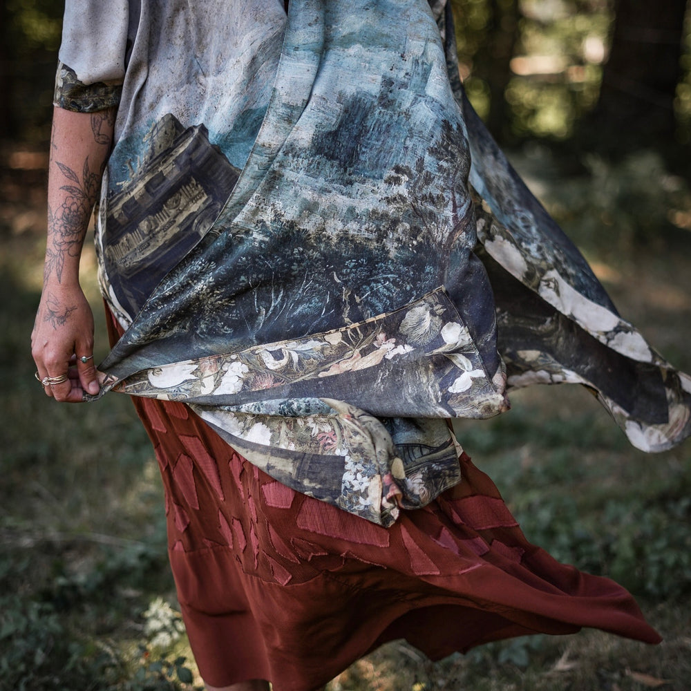 
                  
                    Castles in the Air Starduster kimono featuring Brueghel’s 1600s landscape, classical ruins, and joyful swing scene on bamboo-based viscose – Market of Stars.
                  
                