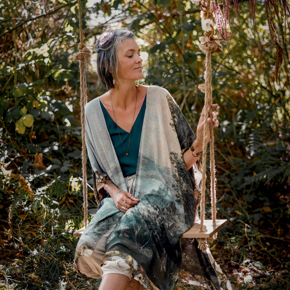
                  
                    Castles in the Air Starduster kimono featuring Brueghel’s 1600s landscape, classical ruins, and joyful swing scene on bamboo-based viscose – Market of Stars.
                  
                