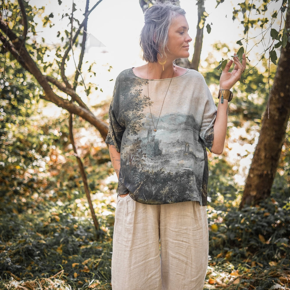 
                  
                    Castles in the Air Luxe Tee featuring Jan Brueghel’s whimsical 1600s landscape and painterly floral trim on soft bamboo-based viscose – Market of Stars.
                  
                
