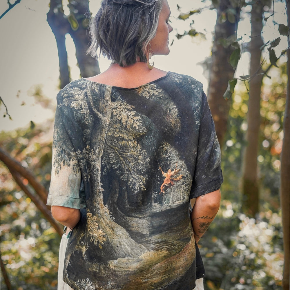 
                  
                    Castles in the Air Luxe Tee featuring Jan Brueghel’s whimsical 1600s landscape and painterly floral trim on soft bamboo-based viscose – Market of Stars.
                  
                