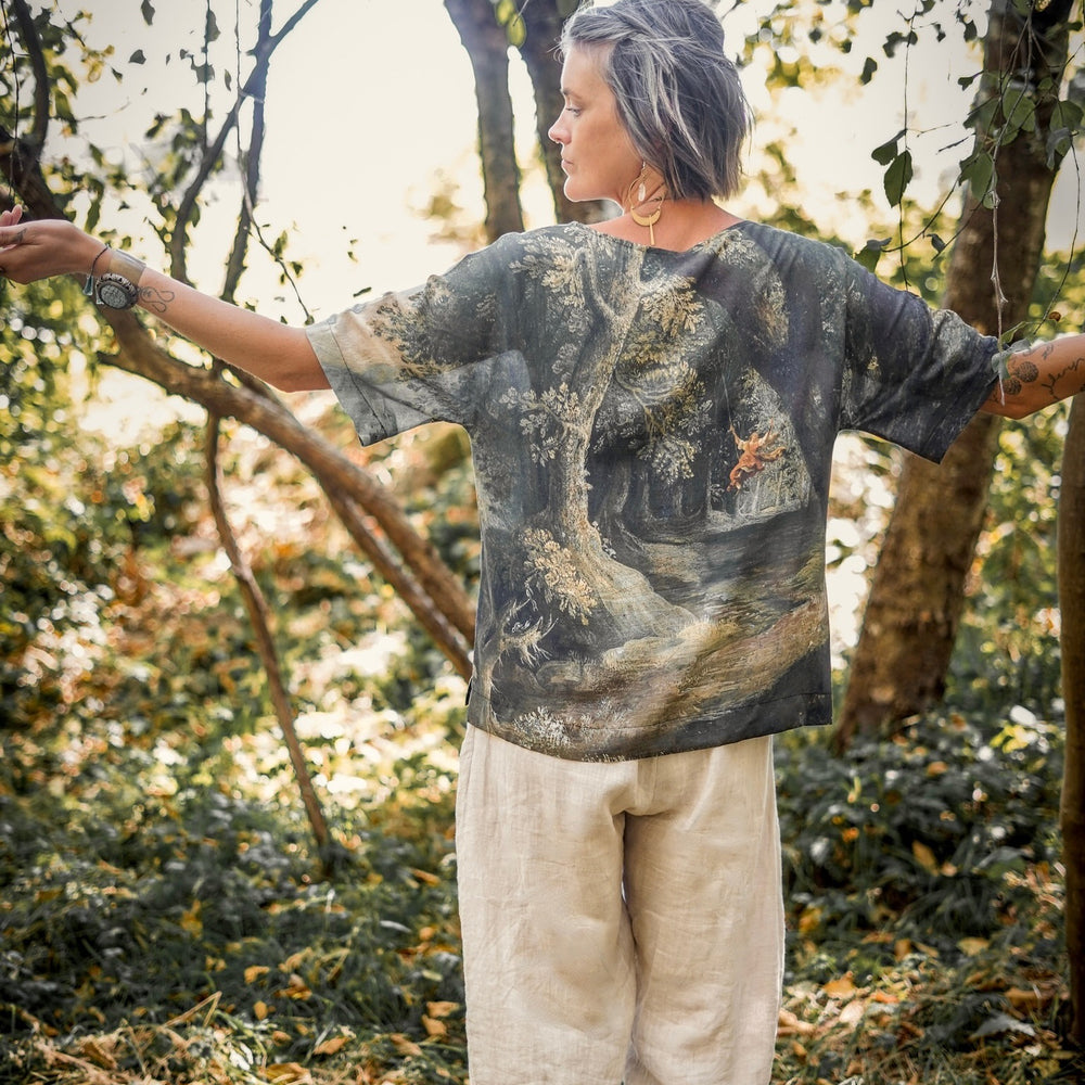 
                  
                    Castles in the Air Luxe Tee featuring Jan Brueghel’s whimsical 1600s landscape and painterly floral trim on soft bamboo-based viscose – Market of Stars.
                  
                