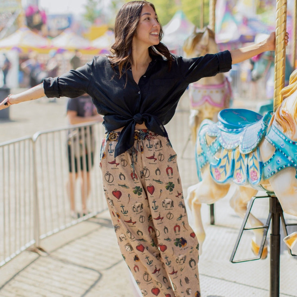 
                  
                    Charmed Life Artist Pants featuring playful Victorian luck charms and floral trim on breathable linen & bamboo/wood viscose – Market of Stars.
                  
                