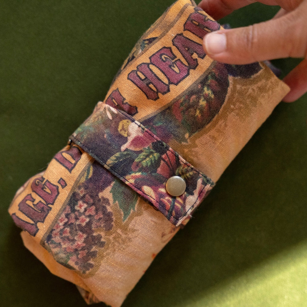 
                  
                    Model holding Take Heart Market Tote featuring Victorian lithographs, Sacred Heart artwork, and “courage, dear heart” script on linen blend fabric – Market of Stars.
                  
                