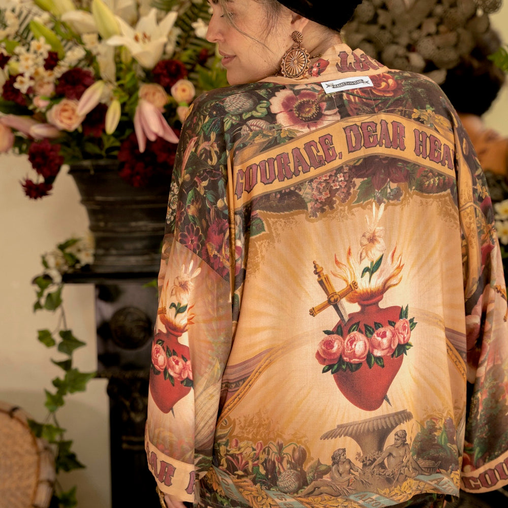 
                  
                    Model wearing Courage Dear Heart Pixie cut Duster featuring Victorian Sacred Heart art and hidden affirmations of courage and love on bamboo-based viscose – Market of Stars.
                  
                