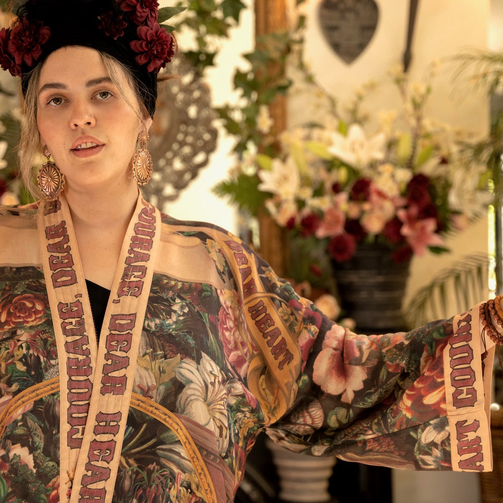 
                  
                    Model wearing Courage Dear Heart Pixie cut Duster featuring Victorian Sacred Heart art and hidden affirmations of courage and love on bamboo-based viscose – Market of Stars.
                  
                
