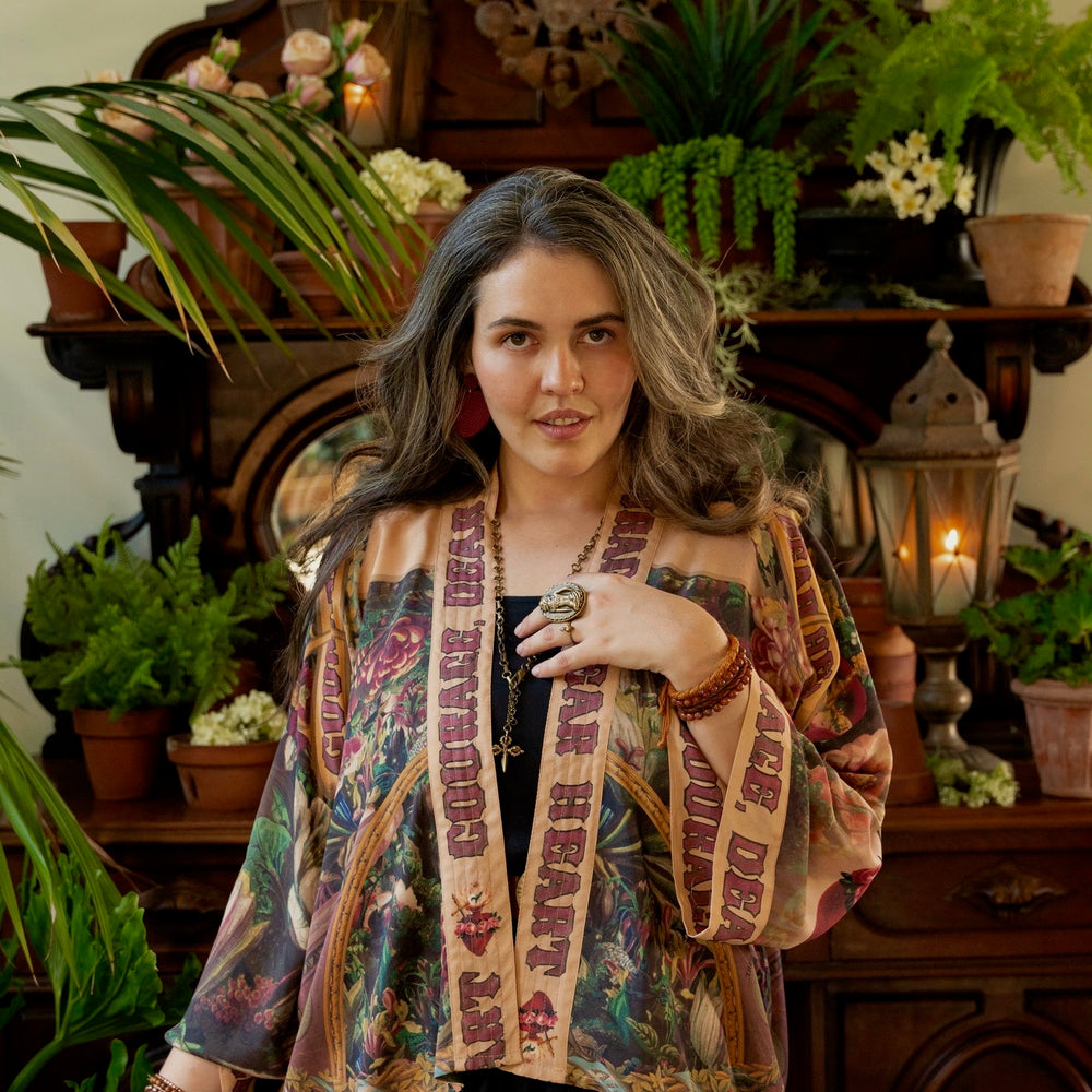 
                  
                    Model wearing Courage Dear Heart Pixie cut Duster featuring Victorian Sacred Heart art and hidden affirmations of courage and love on bamboo-based viscose – Market of Stars.
                  
                