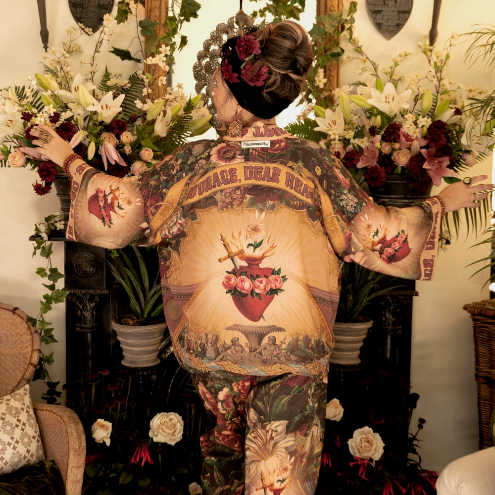 
                  
                    Model wearing Courage Dear Heart Pixie cut Duster featuring Victorian Sacred Heart art and hidden affirmations of courage and love on bamboo-based viscose – Market of Stars.
                  
                