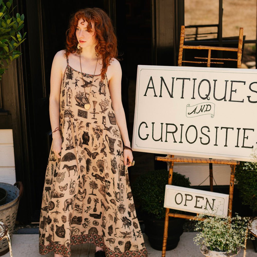 
                  
                    Model wearing a maxi-length bamboo viscose slip dress inspired by a mysterious Victorian scrapbook. This whimsical print celebrates the wonder hidden in ordinary things — Market of Stars.
                  
                