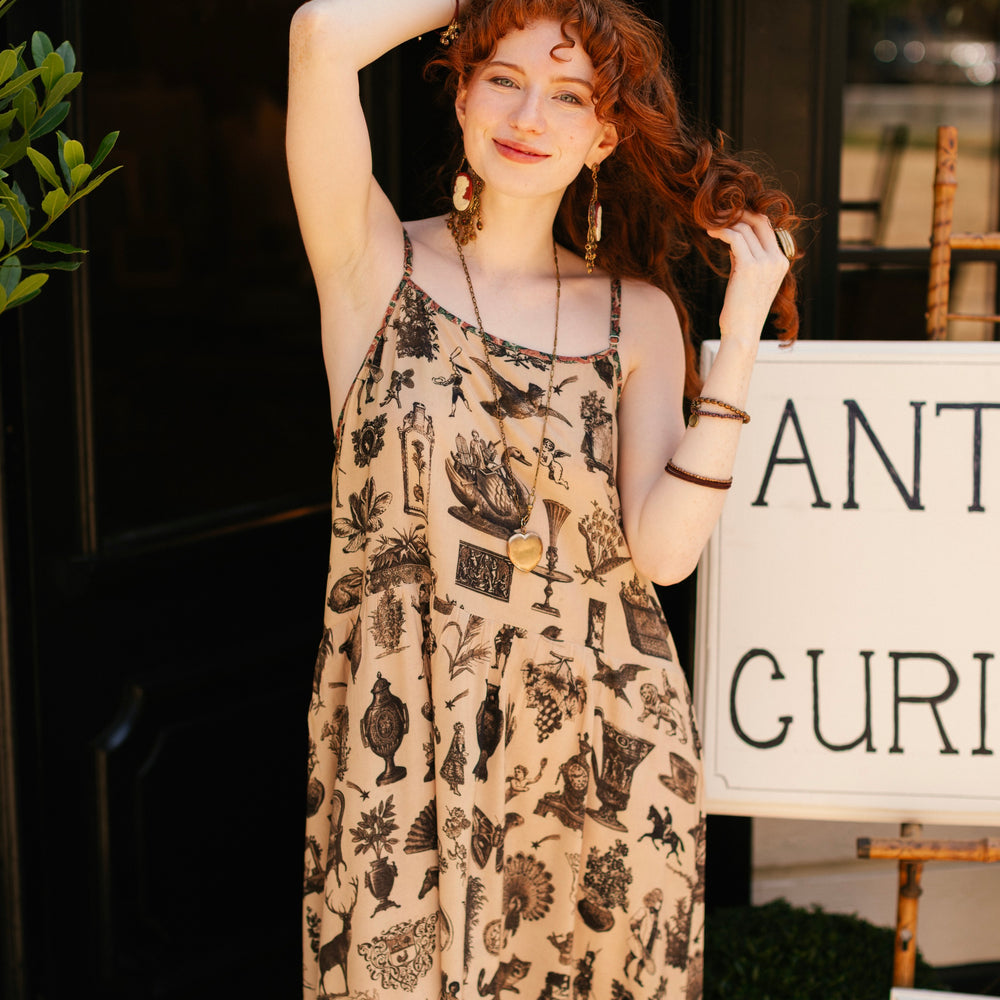 
                  
                    Model wearing a maxi-length bamboo viscose slip dress inspired by a mysterious Victorian scrapbook. This whimsical print celebrates the wonder hidden in ordinary things — Market of Stars.
                  
                