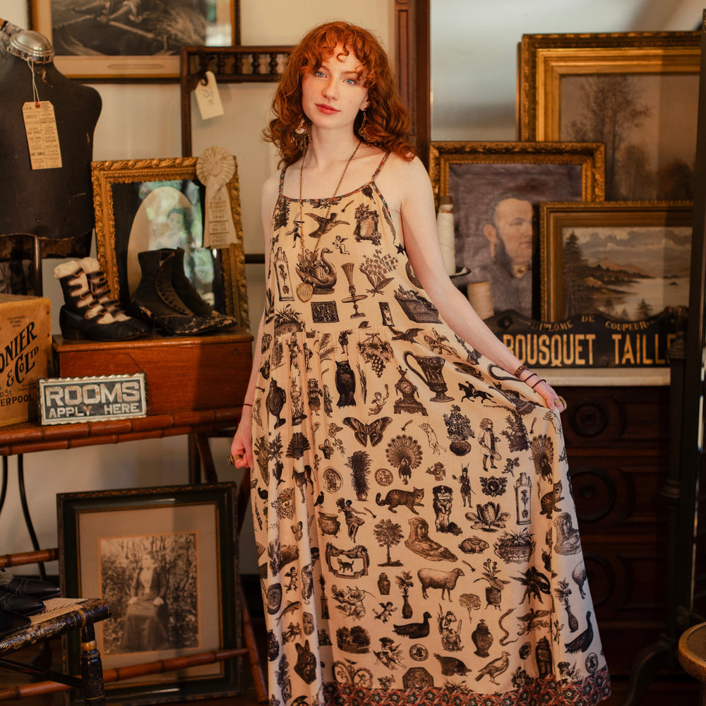 
                  
                    Model wearing a maxi-length bamboo viscose slip dress inspired by a mysterious Victorian scrapbook. This whimsical print celebrates the wonder hidden in ordinary things — Market of Stars.
                  
                