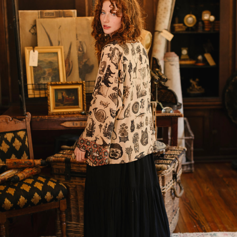 
                  
                    Model wearing a bamboo-viscose cropped length duster inspired by a mysterious Victorian scrapbook. This whimsical print celebrates the wonder hidden in ordinary things — Market of Stars.
                  
                