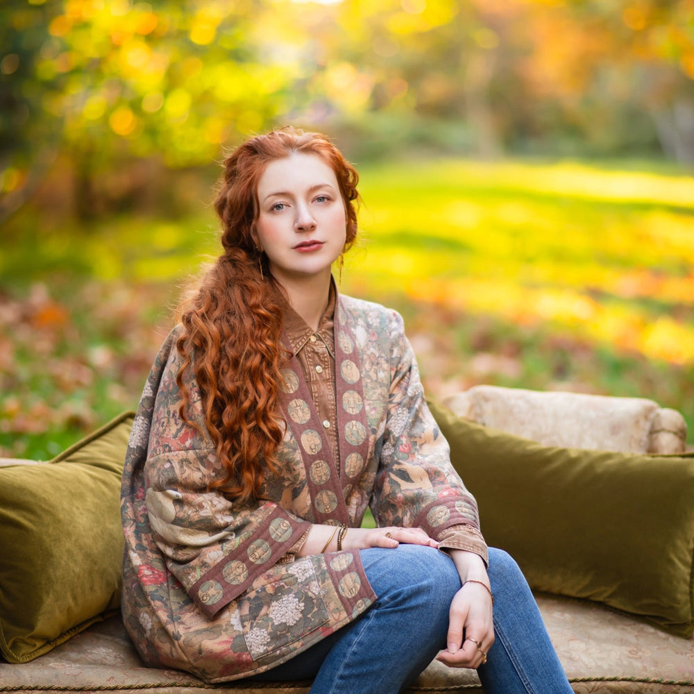 
                  
                    Model wearing Dreamweaver Cottage Cardigan featuring Mucha’s 1896 zodiac woman with celestial crown, printed on cozy fleece-lined cotton blend – Market of Stars
                  
                