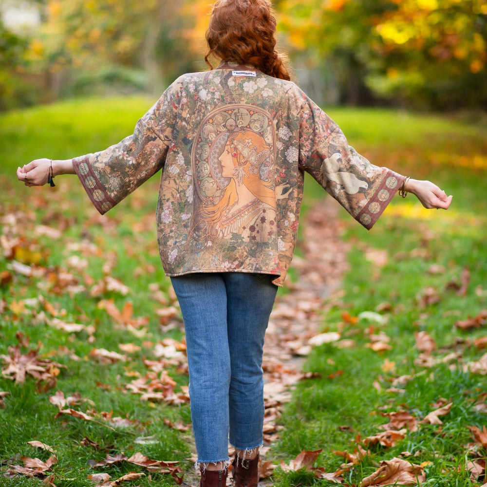 
                  
                    Model wearing Dreamweaver Cottage Cardigan featuring Mucha’s 1896 zodiac woman with celestial crown, printed on cozy fleece-lined cotton blend – Market of Stars
                  
                