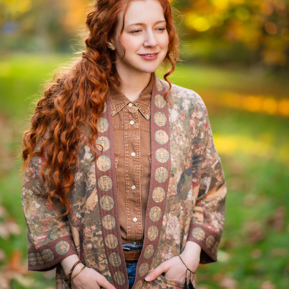 
                  
                    Model wearing Dreamweaver Cottage Cardigan featuring Mucha’s 1896 zodiac woman with celestial crown, printed on cozy fleece-lined cotton blend – Market of Stars
                  
                