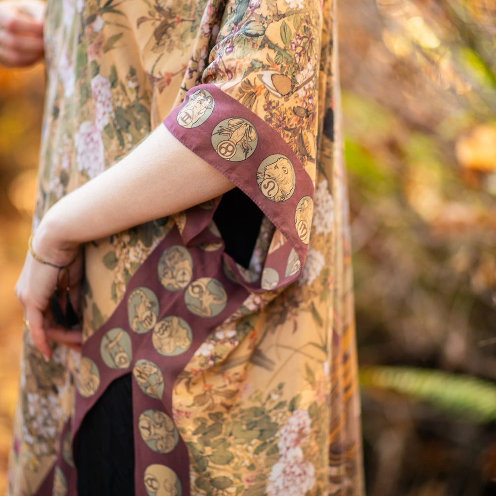 
                  
                    Dreamweaver Goddess Duster featuring Alphonse Mucha’s 1896 zodiac woman, celestial crown, and burgundy zodiac trim inspired by vintage bohemian style – Market of Stars
                  
                