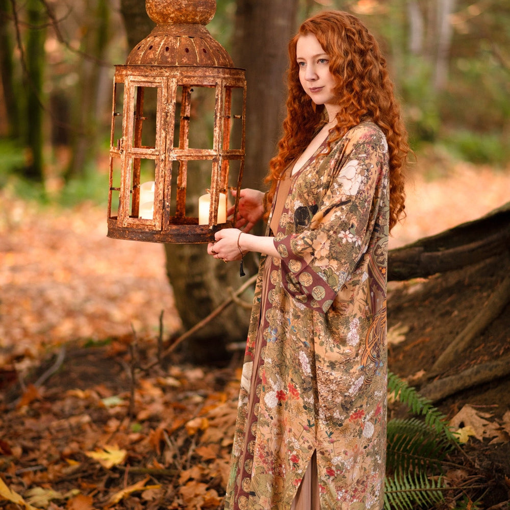 
                  
                    Model wearing Dreamweaver Opera Duster – featuring Alphonse Mucha’s zodiac woman, celestial crown, and burgundy zodiac trim inspired by 1970s luxe bohemian style – Market of Stars.
                  
                