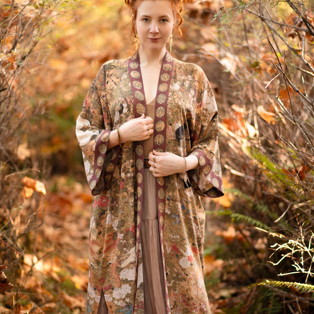 
                  
                    Model wearing Dreamweaver Opera Duster – featuring Alphonse Mucha’s zodiac woman, celestial crown, and burgundy zodiac trim inspired by 1970s luxe bohemian style – Market of Stars.
                  
                