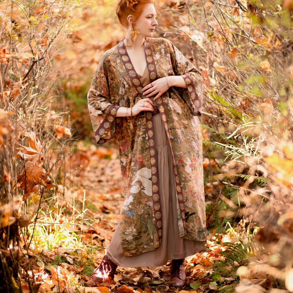 
                  
                    Model wearing Dreamweaver Opera Duster – featuring Alphonse Mucha’s zodiac woman, celestial crown, and burgundy zodiac trim inspired by 1970s luxe bohemian style – Market of Stars.
                  
                