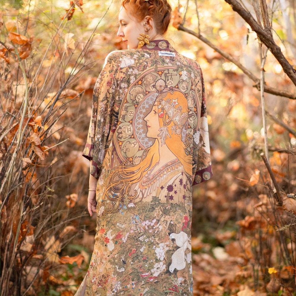 
                  
                    Model wearing Dreamweaver Opera Duster – featuring Alphonse Mucha’s zodiac woman, celestial crown, and burgundy zodiac trim inspired by 1970s luxe bohemian style – Market of Stars.
                  
                