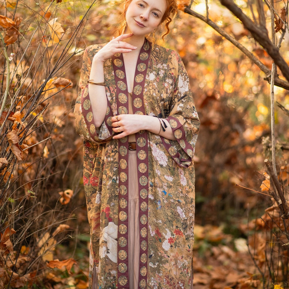 
                  
                    Model wearing Dreamweaver Opera Duster – featuring Alphonse Mucha’s zodiac woman, celestial crown, and burgundy zodiac trim inspired by 1970s luxe bohemian style – Market of Stars.
                  
                