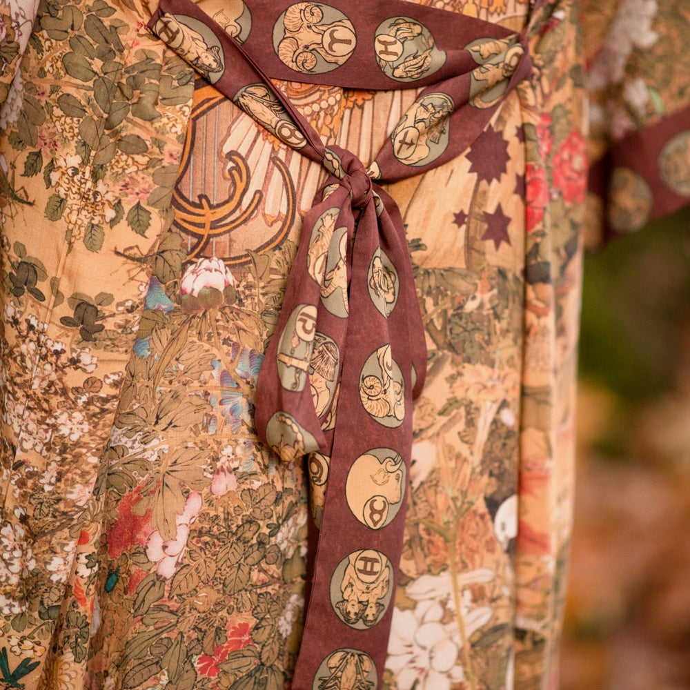 
                  
                    Model wearing Dreamweaver Opera Duster – featuring Alphonse Mucha’s zodiac woman, celestial crown, and burgundy zodiac trim inspired by 1970s luxe bohemian style – Market of Stars.
                  
                