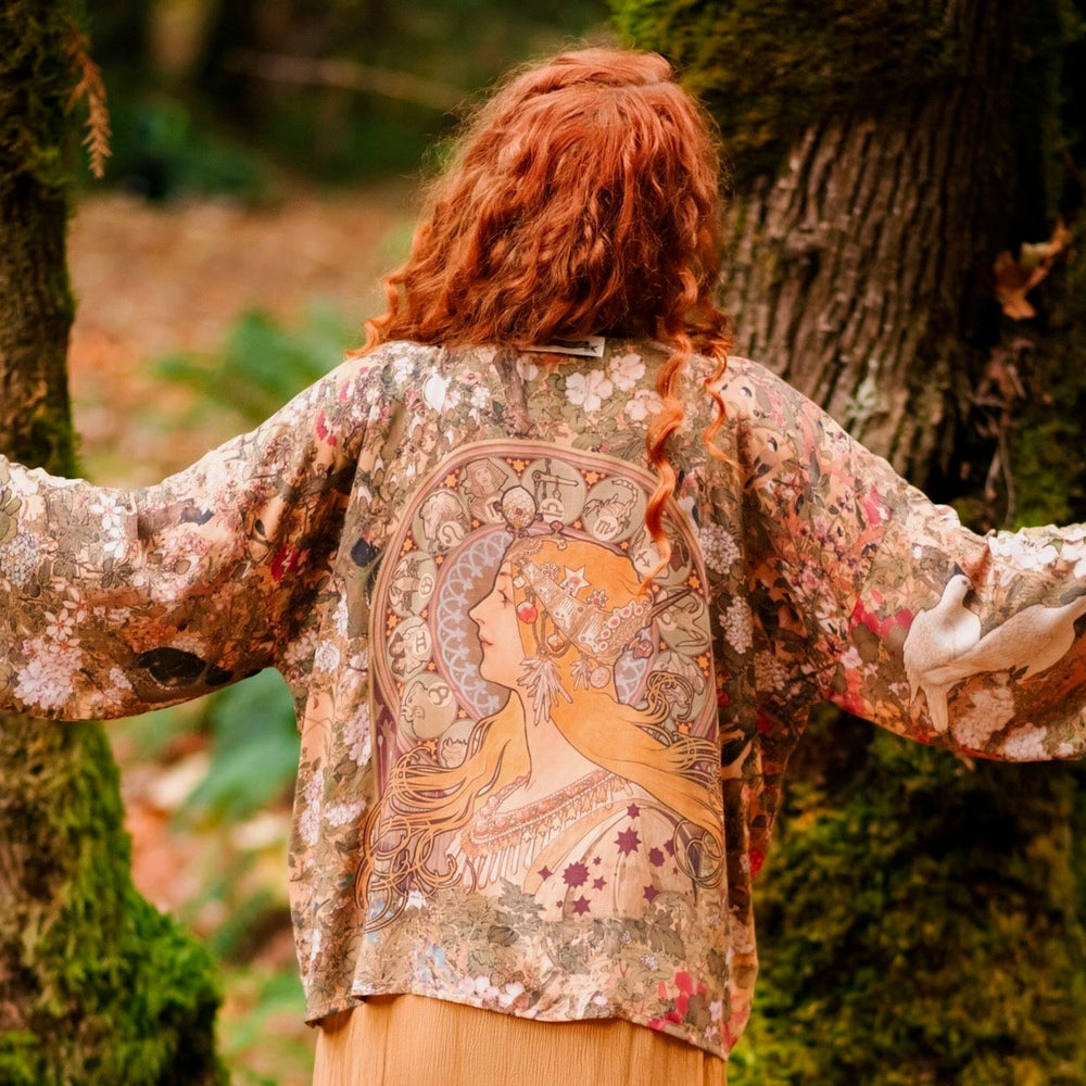 
                  
                    Model wearing Dreamweaver Matinée Duster featuring Alphonse Mucha’s 1896 zodiac woman – trimmed with celestial symbols on deep burgundy background – Market of Stars.
                  
                