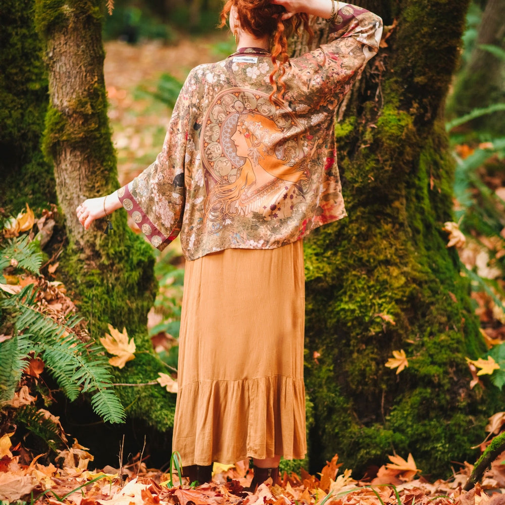 
                  
                    Model wearing Dreamweaver Matinée Duster featuring Alphonse Mucha’s 1896 zodiac woman – trimmed with celestial symbols on deep burgundy background – Market of Stars.
                  
                
