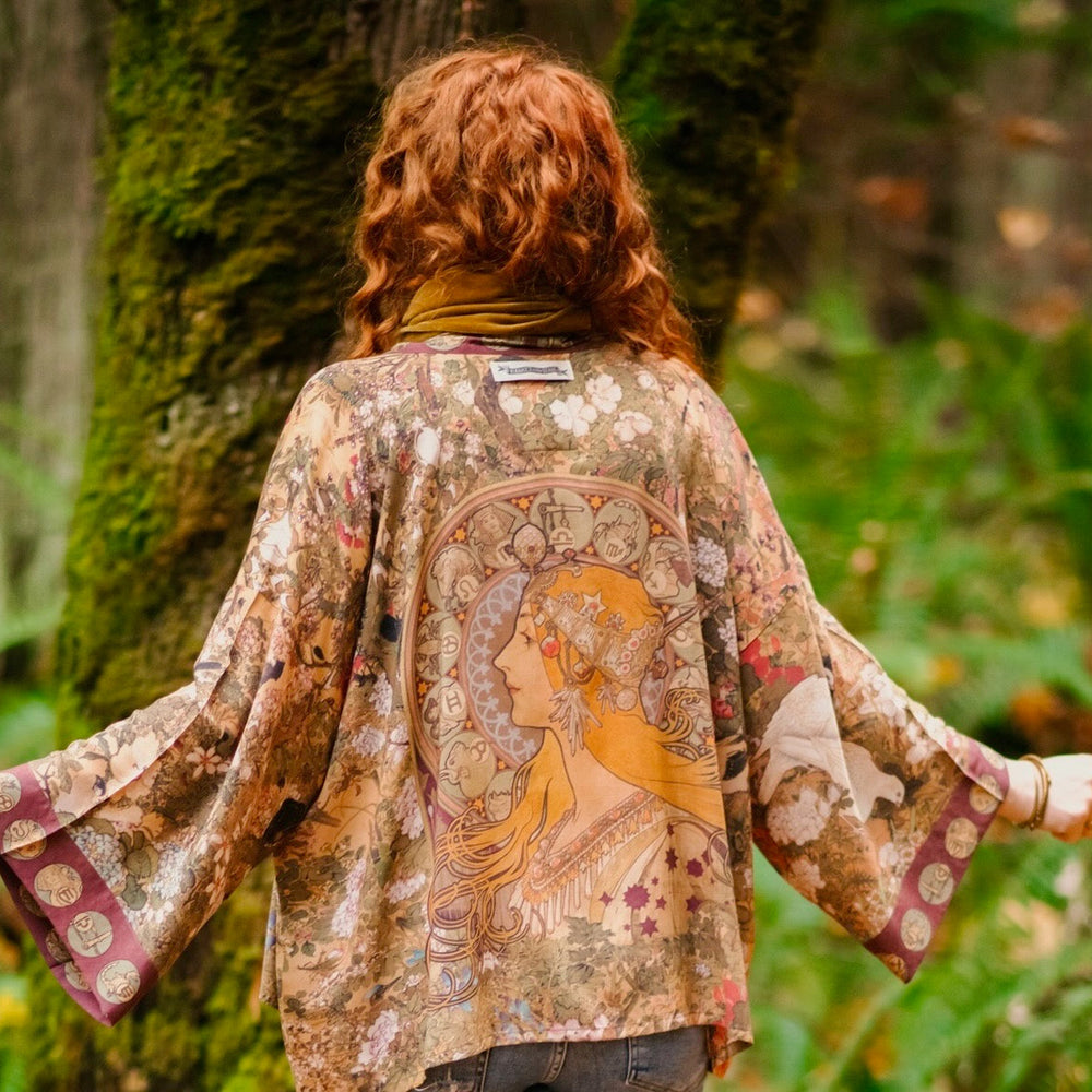 
                  
                    Model wearing Dreamweaver Matinée Duster featuring Alphonse Mucha’s 1896 zodiac woman – trimmed with celestial symbols on deep burgundy background – Market of Stars.
                  
                