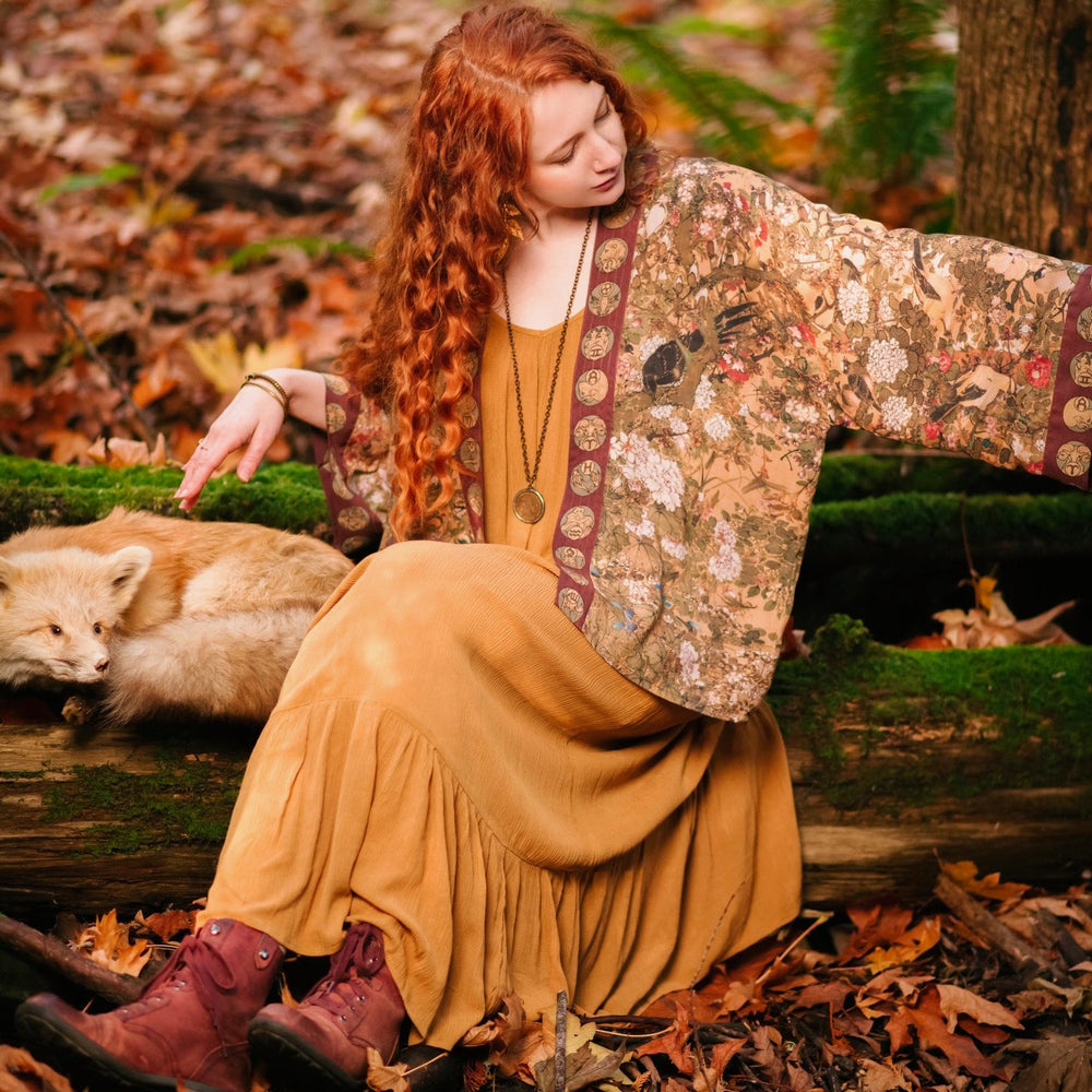 
                  
                    Model wearing Dreamweaver Matinée Duster featuring Alphonse Mucha’s 1896 zodiac woman – trimmed with celestial symbols on deep burgundy background – Market of Stars.
                  
                