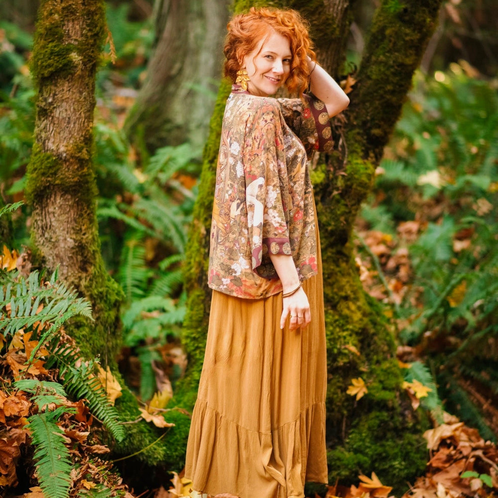 
                  
                    Model wearing Dreamweaver Matinée Duster featuring Alphonse Mucha’s 1896 zodiac woman – trimmed with celestial symbols on deep burgundy background – Market of Stars.
                  
                