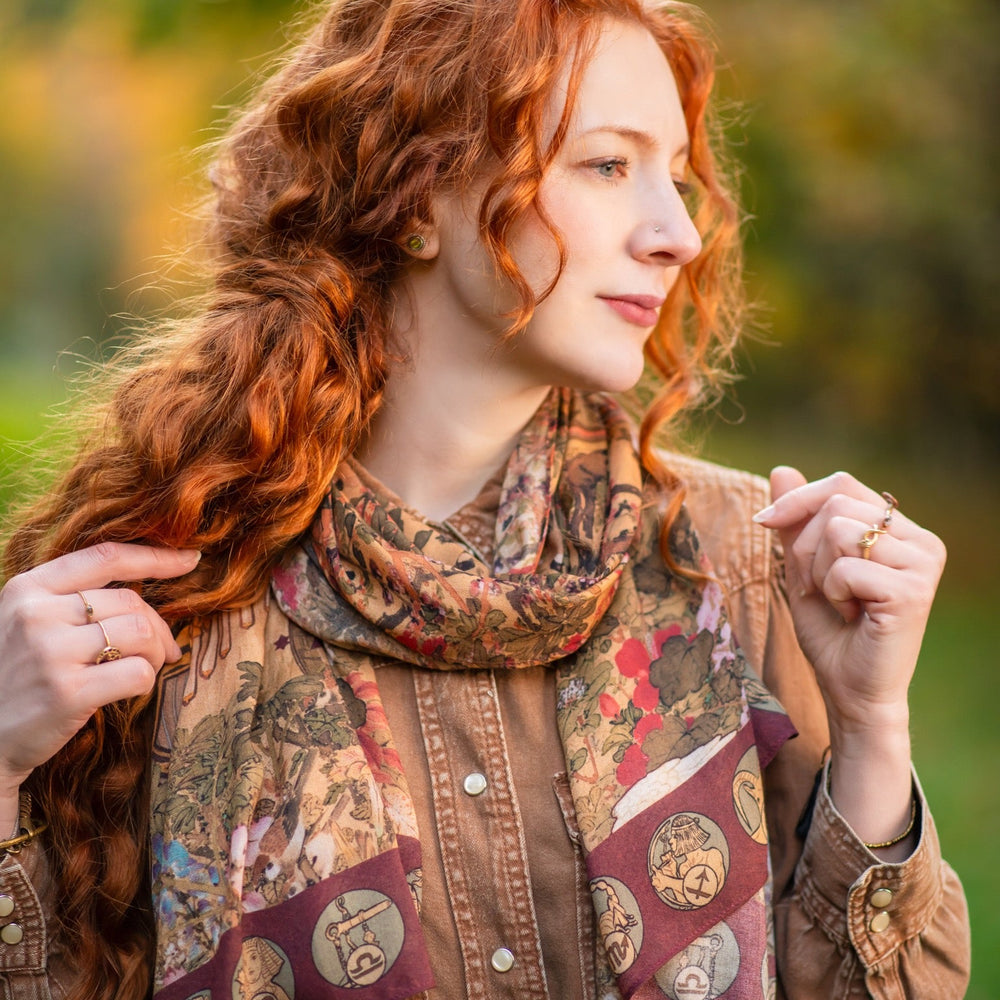 Model wearing Dreamweaver Zodiac Scarf – featuring Alphonse Mucha’s 1896 celestial woman surrounded by zodiac signs and floral scroll artwork – Market of Stars.