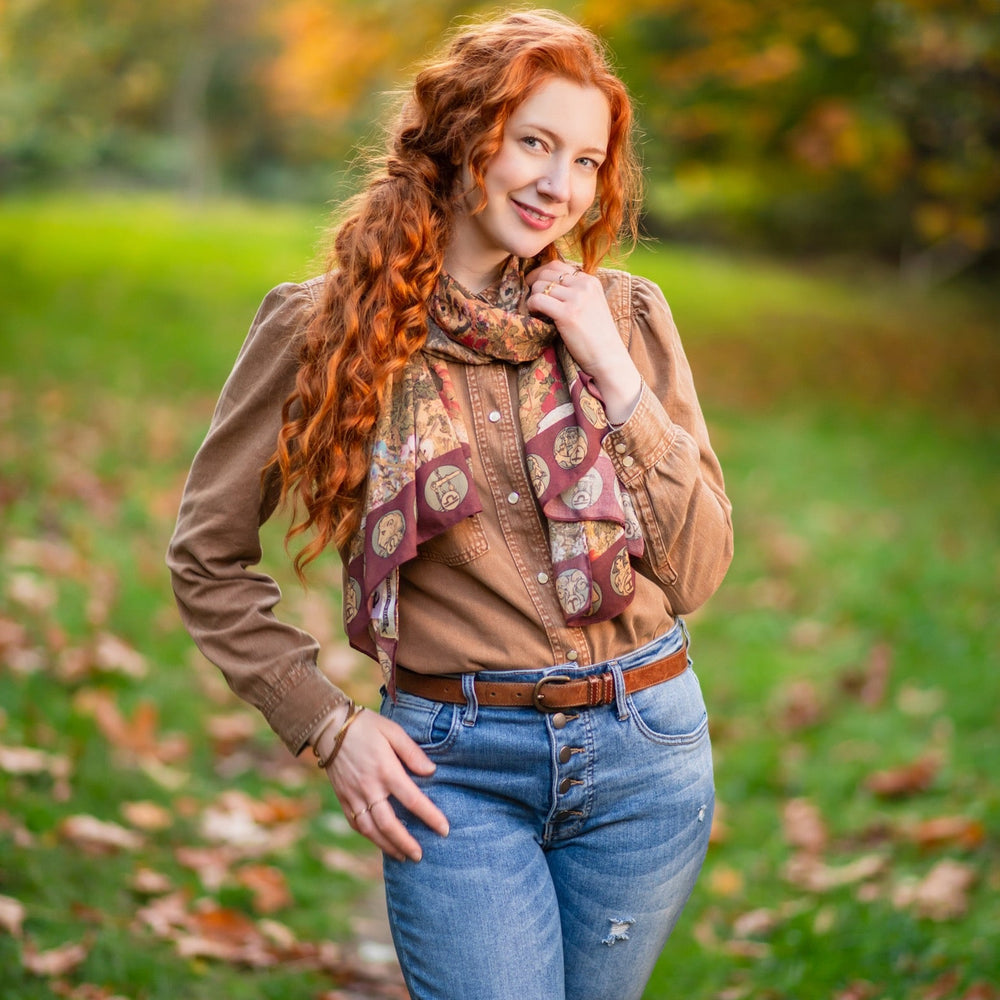 
                  
                    Model wearing Dreamweaver Zodiac Scarf – featuring Alphonse Mucha’s 1896 celestial woman surrounded by zodiac signs and floral scroll artwork – Market of Stars.
                  
                