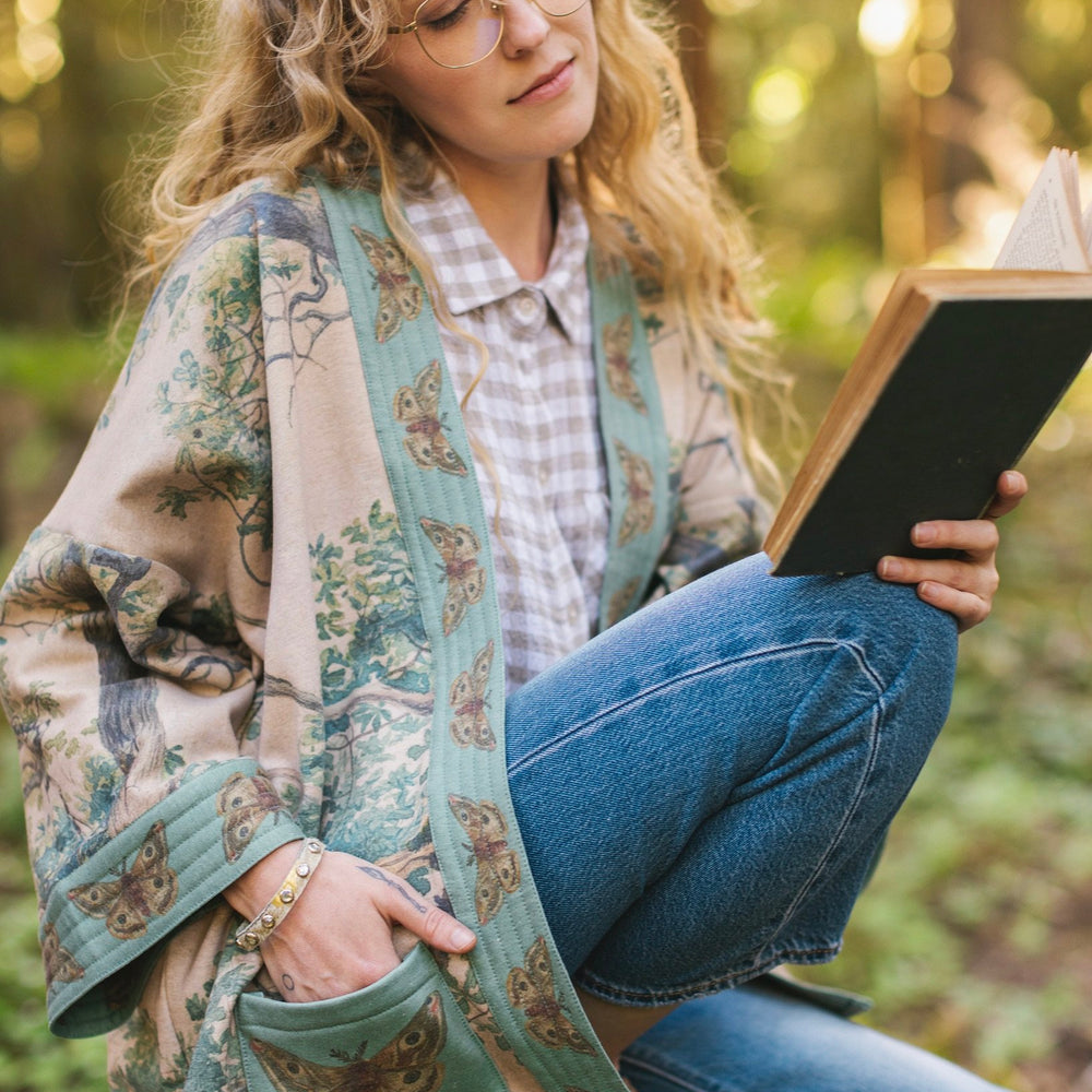 Model wearing Earth and Sky Cottage Jacket – featuring Charles Aston’s tree painting and antique moth art – cozy fleece-lined cardigan for cooler days – Market of Stars.