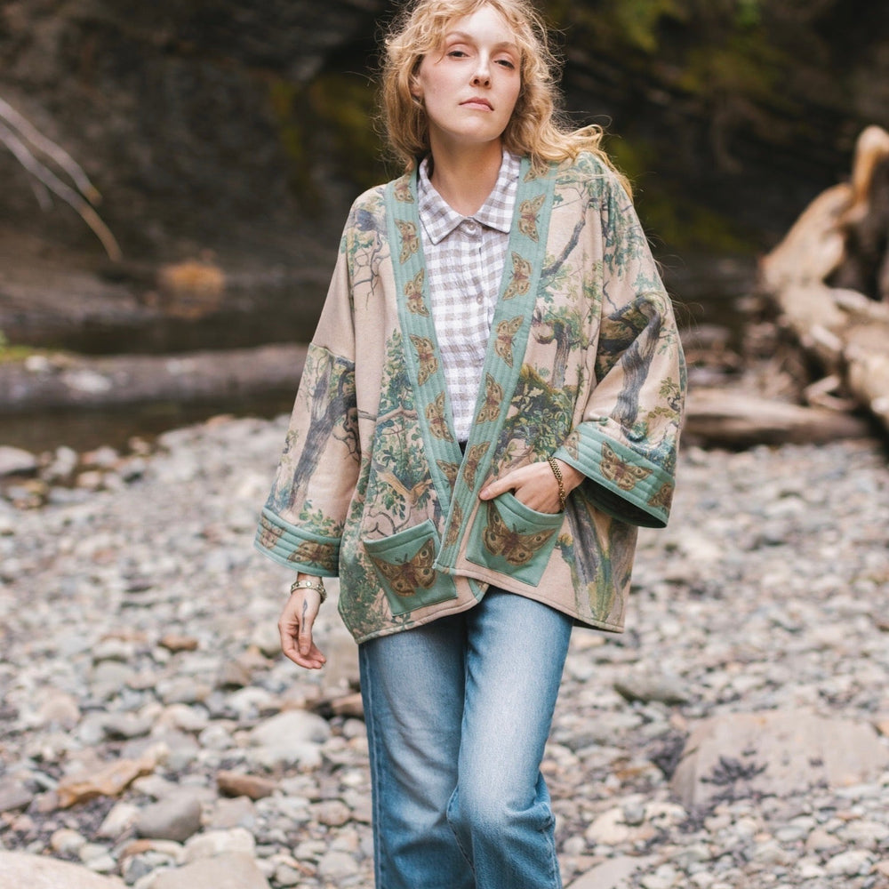 
                  
                    Model wearing Earth and Sky Cottage Jacket – featuring Charles Aston’s tree painting and antique moth art – cozy fleece-lined cardigan for cooler days – Market of Stars.
                  
                