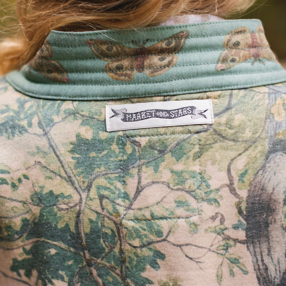 
                  
                    Model wearing Earth and Sky Cottage Jacket – featuring Charles Aston’s tree painting and antique moth art – cozy fleece-lined cardigan for cooler days – Market of Stars.
                  
                
