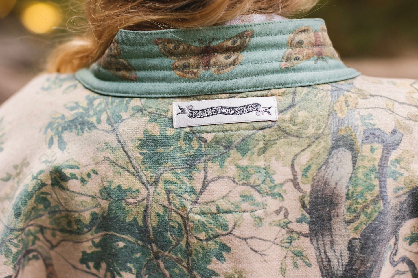 Model wearing Earth and Sky Cottage Jacket – featuring Charles Aston’s tree painting and antique moth art – cozy fleece-lined cardigan for cooler days – Market of Stars.