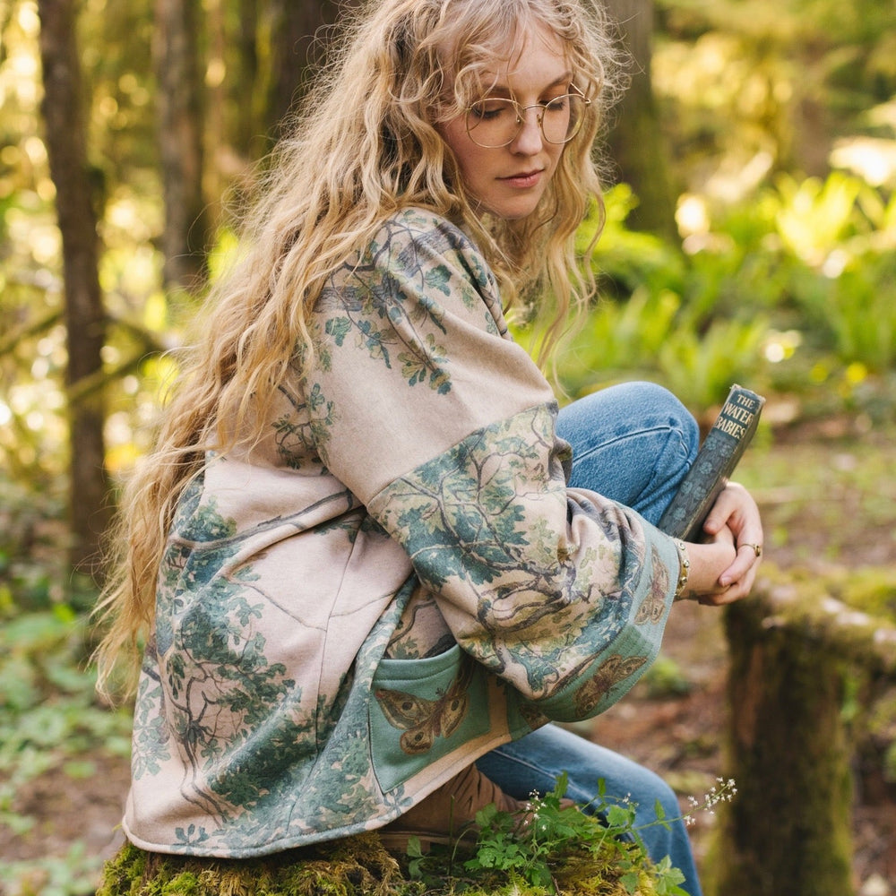
                  
                    Model wearing Earth and Sky Cottage Jacket – featuring Charles Aston’s tree painting and antique moth art – cozy fleece-lined cardigan for cooler days – Market of Stars.
                  
                