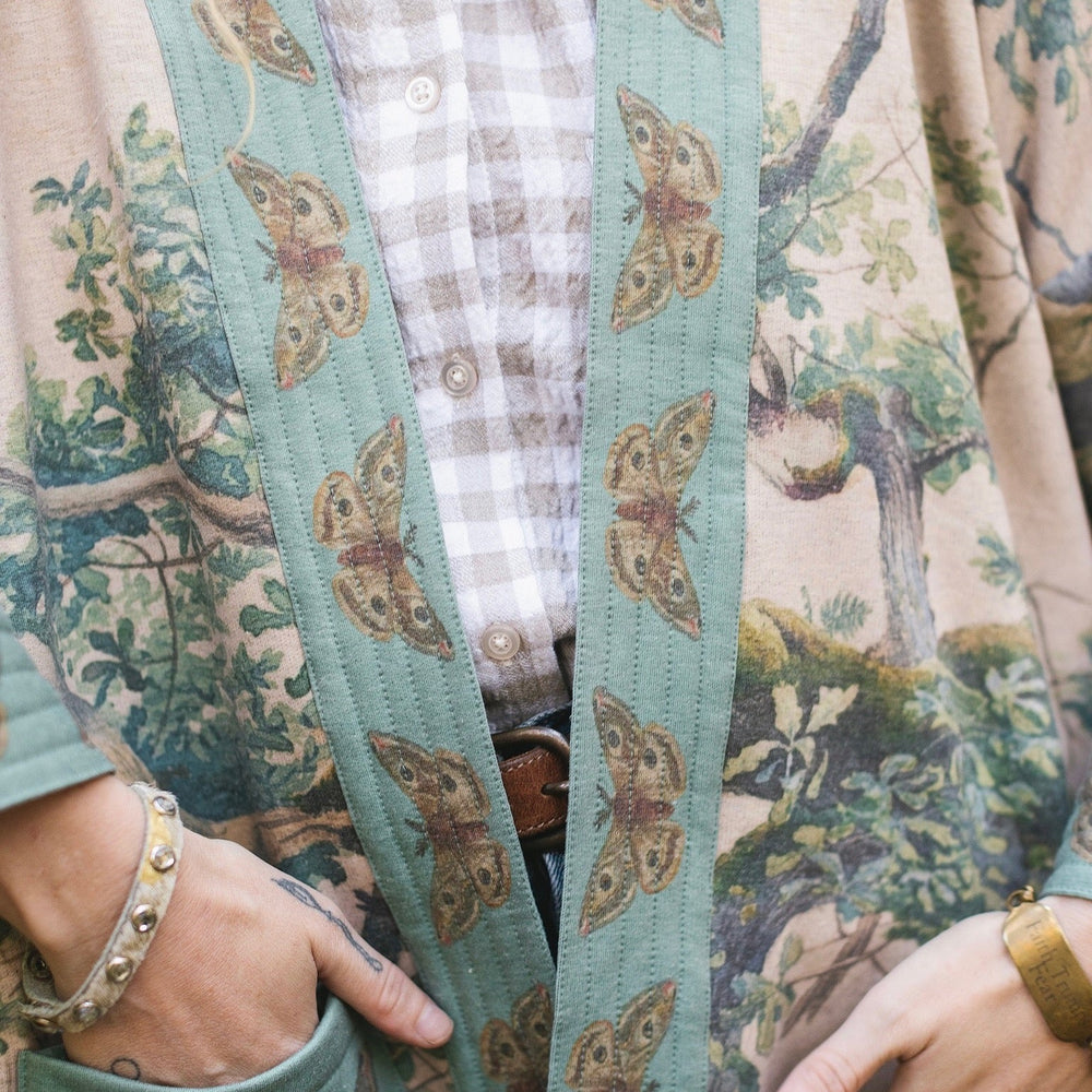 
                  
                    Model wearing Earth and Sky Cottage Jacket – featuring Charles Aston’s tree painting and antique moth art – cozy fleece-lined cardigan for cooler days – Market of Stars.
                  
                