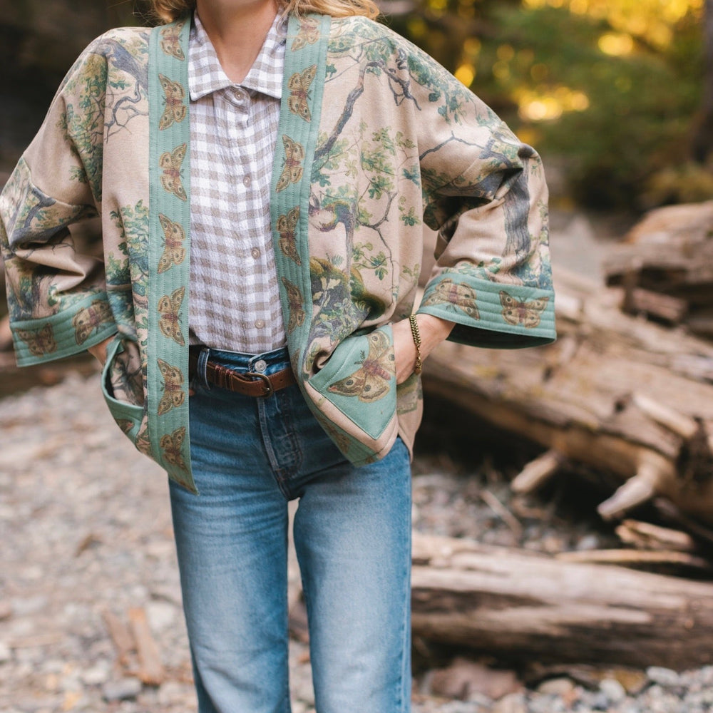 
                  
                    Model wearing Earth and Sky Cottage Jacket – featuring Charles Aston’s tree painting and antique moth art – cozy fleece-lined cardigan for cooler days – Market of Stars.
                  
                