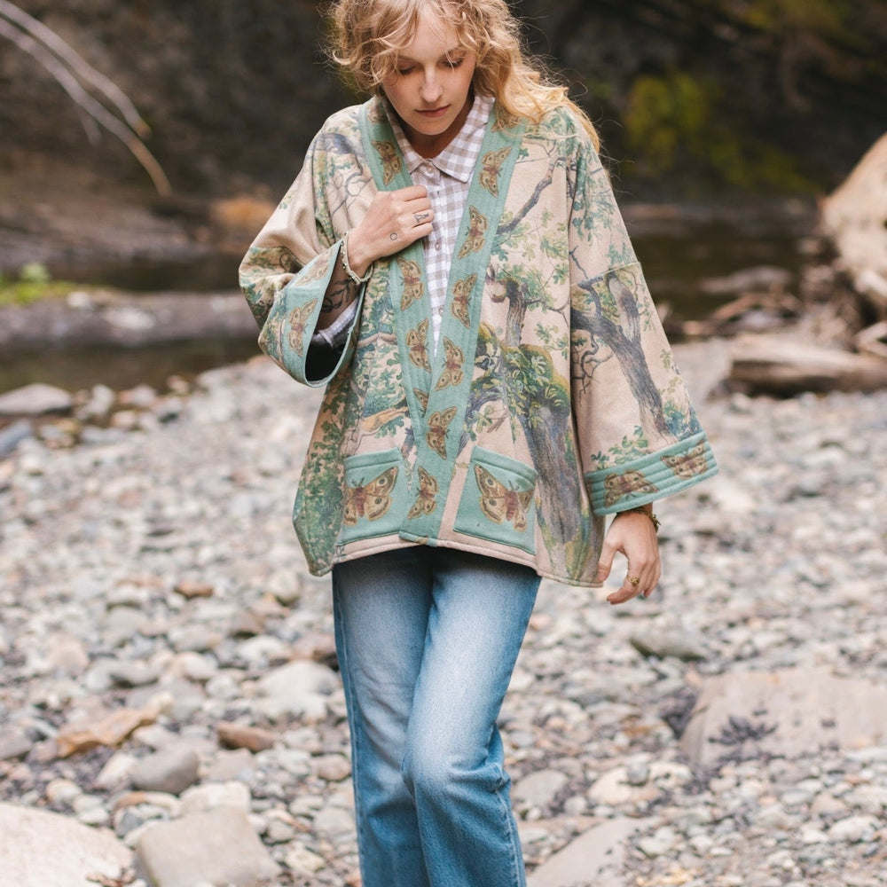 
                  
                    Model wearing Earth and Sky Cottage Jacket – featuring Charles Aston’s tree painting and antique moth art – cozy fleece-lined cardigan for cooler days – Market of Stars.
                  
                