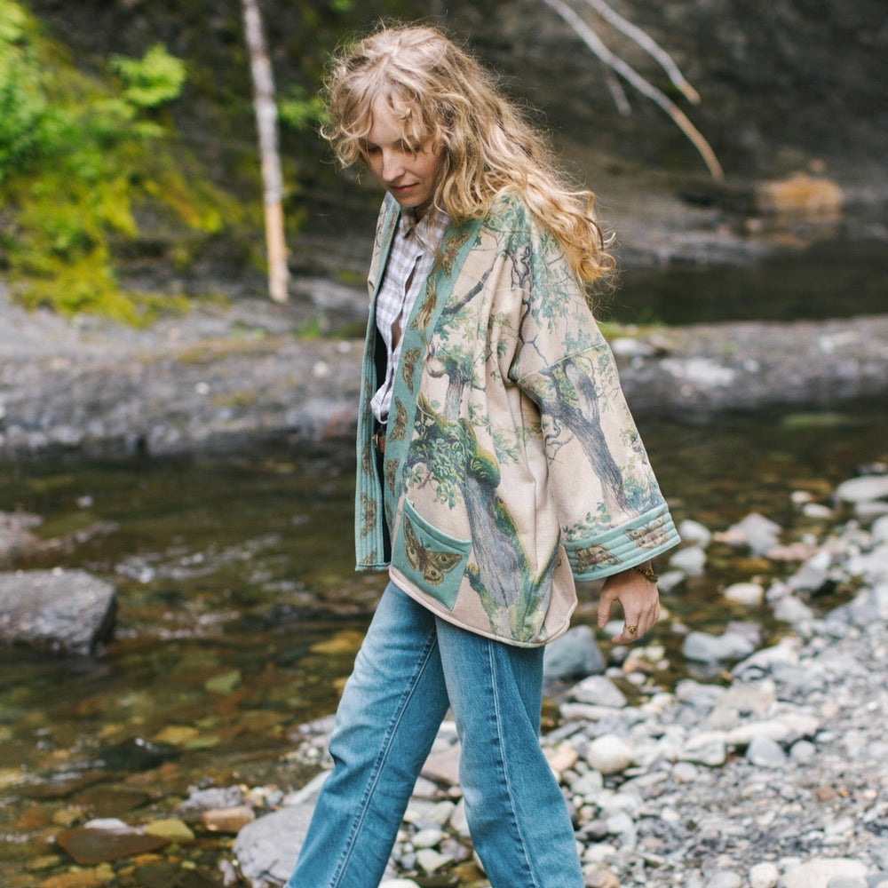 
                  
                    Model wearing Earth and Sky Cottage Jacket – featuring Charles Aston’s tree painting and antique moth art – cozy fleece-lined cardigan for cooler days – Market of Stars.
                  
                