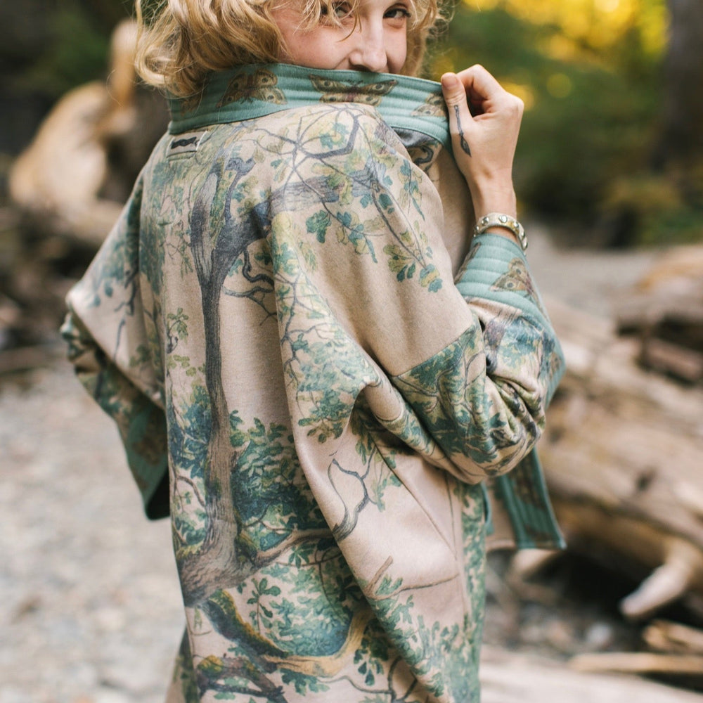 
                  
                    Model wearing Earth and Sky Cottage Jacket – featuring Charles Aston’s tree painting and antique moth art – cozy fleece-lined cardigan for cooler days – Market of Stars.
                  
                