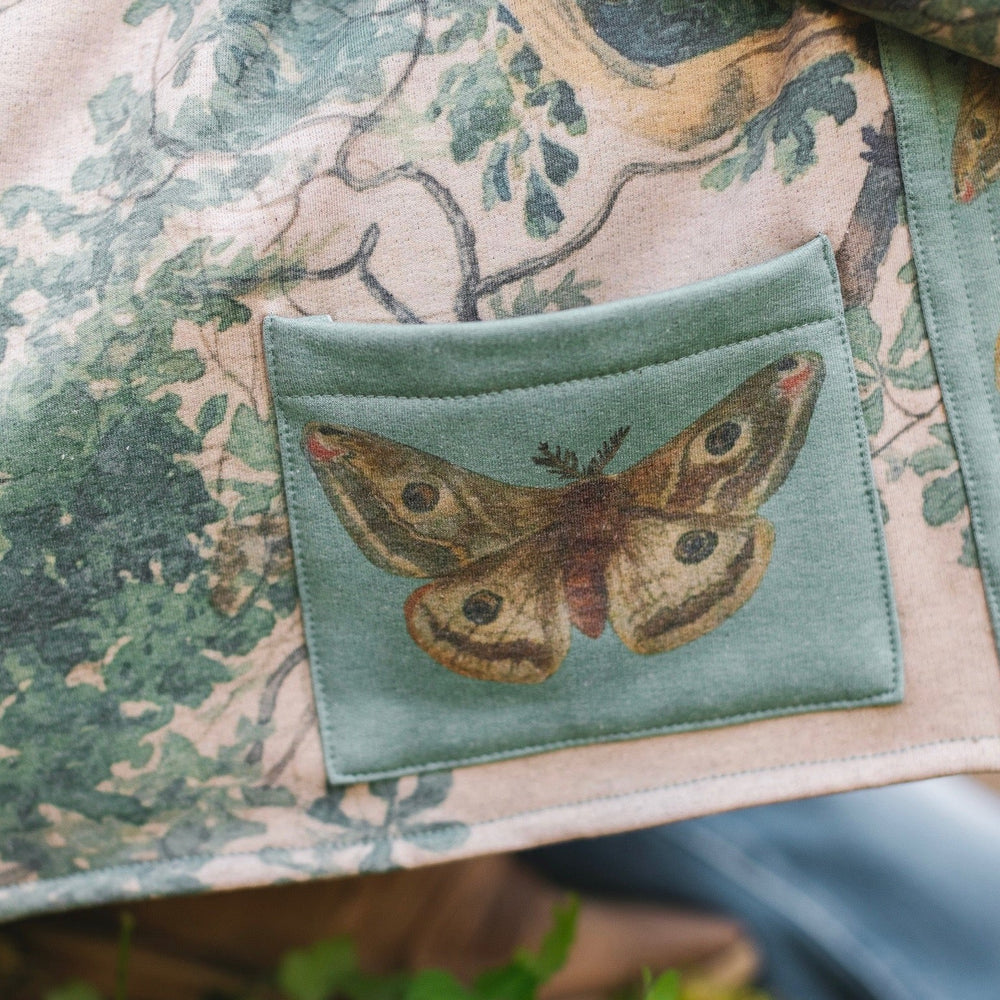 
                  
                    Model wearing Earth and Sky Cottage Jacket – featuring Charles Aston’s tree painting and antique moth art – cozy fleece-lined cardigan for cooler days – Market of Stars.
                  
                