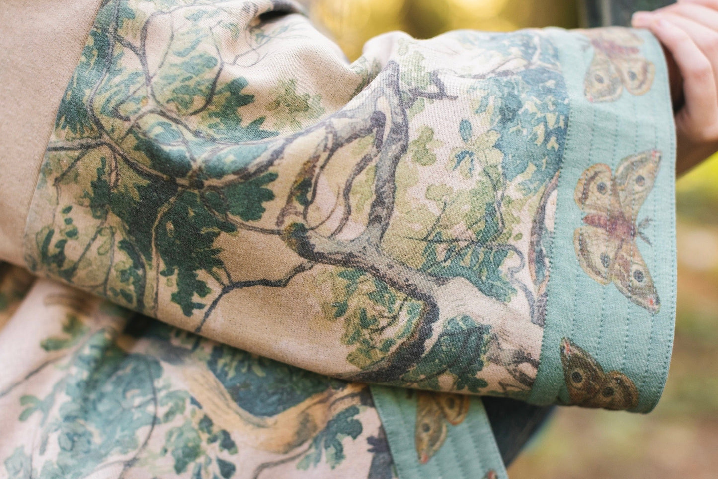 Model wearing Earth and Sky Cottage Jacket – featuring Charles Aston’s tree painting and antique moth art – cozy fleece-lined cardigan for cooler days – Market of Stars.
