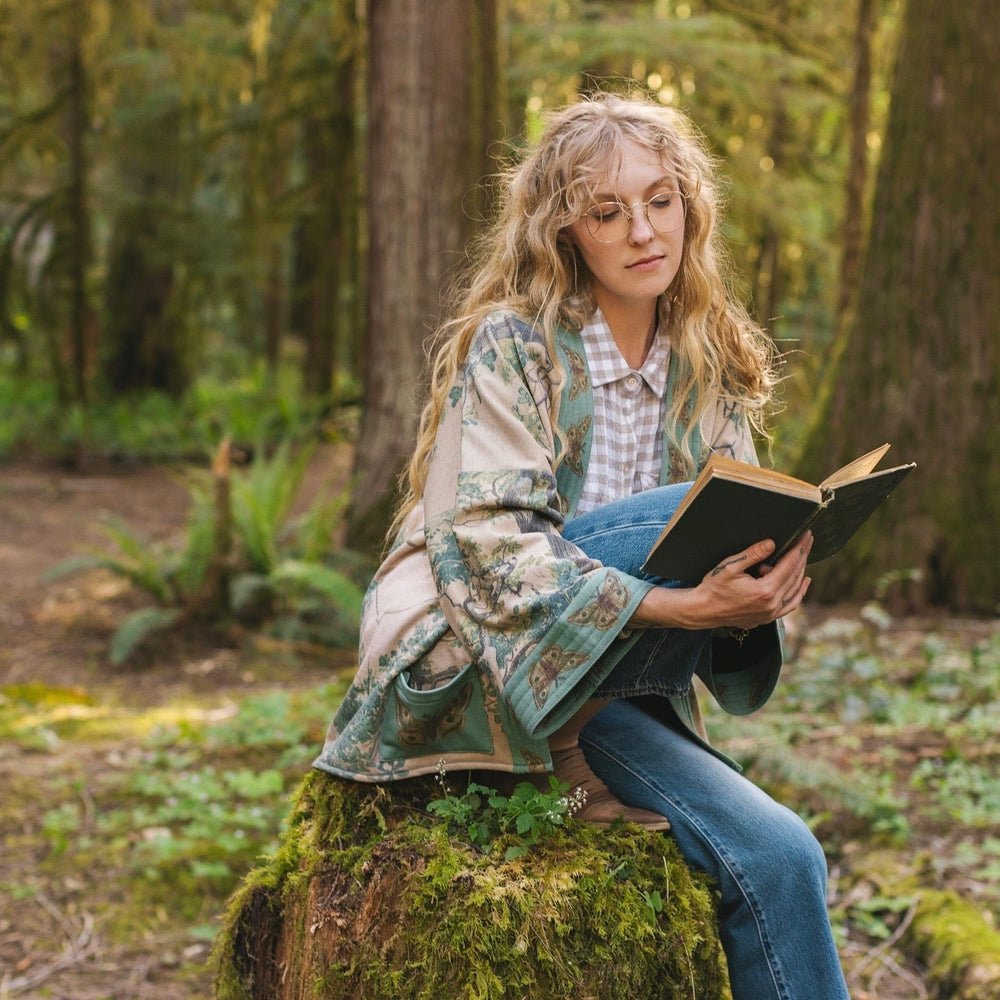 
                  
                    Model wearing Earth and Sky Cottage Jacket – featuring Charles Aston’s tree painting and antique moth art – cozy fleece-lined cardigan for cooler days – Market of Stars.
                  
                