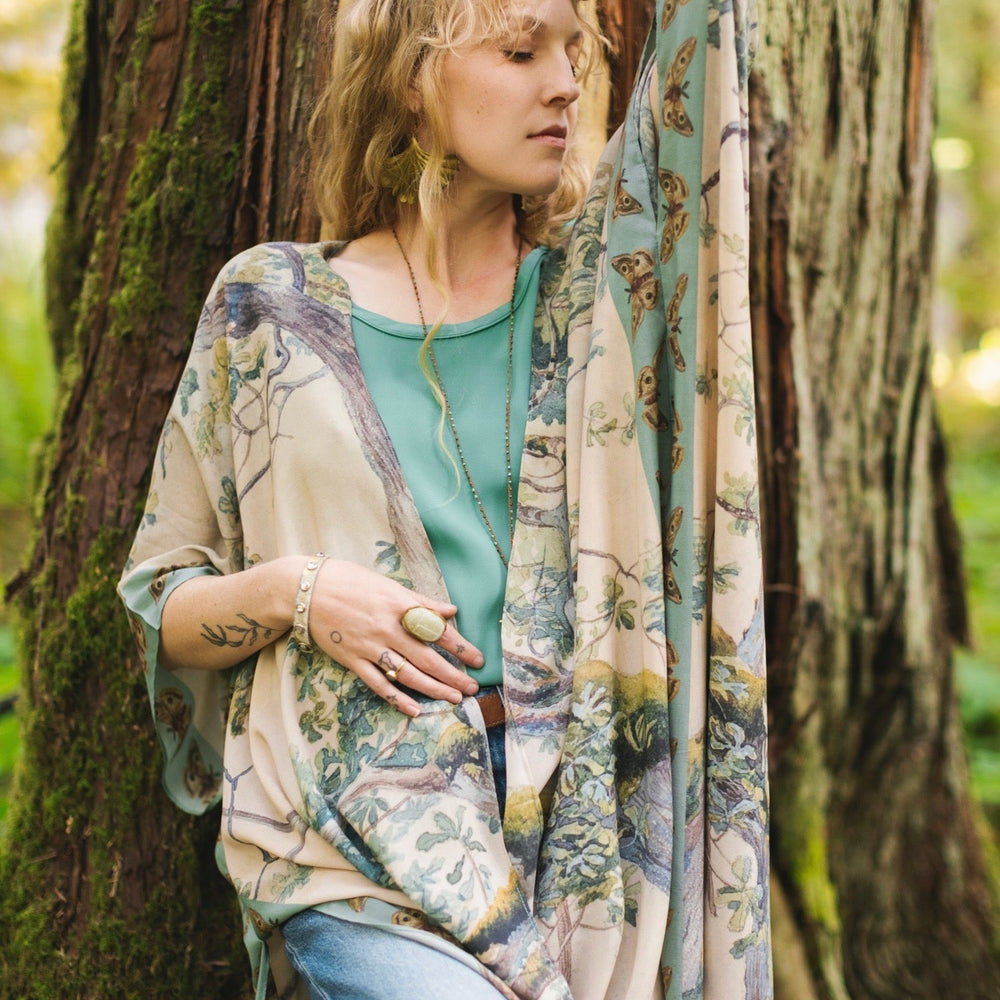 
                  
                    Model wearing the Earth and Sky Goddess length kimono featuring majestic trees by Charles Aston and antique moth illustrations – a dreamy tribute to nature – Market of Stars.
                  
                